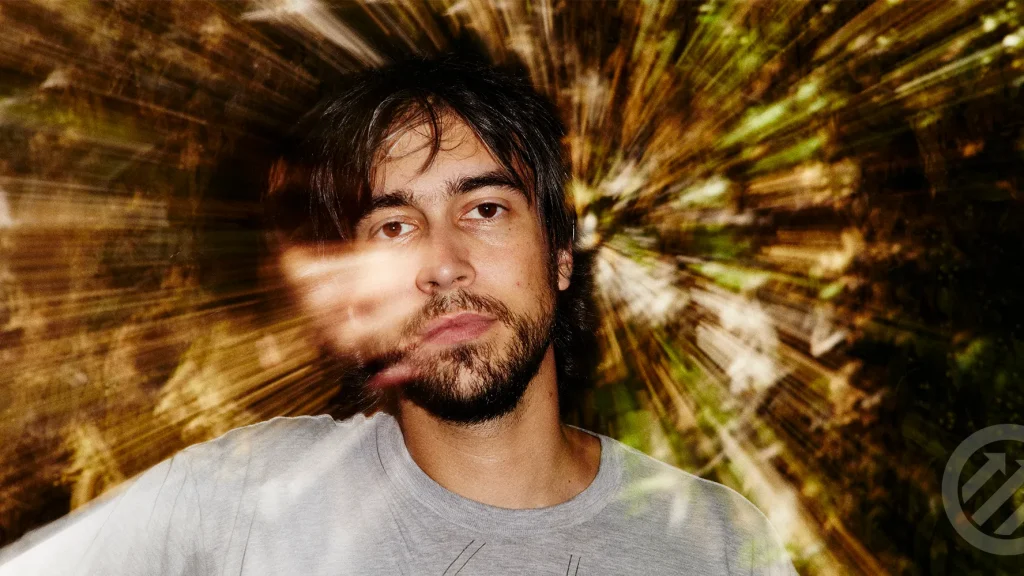 Alex G performing live on stage with a guitar, known for his introspective indie music and abstract lyrics.