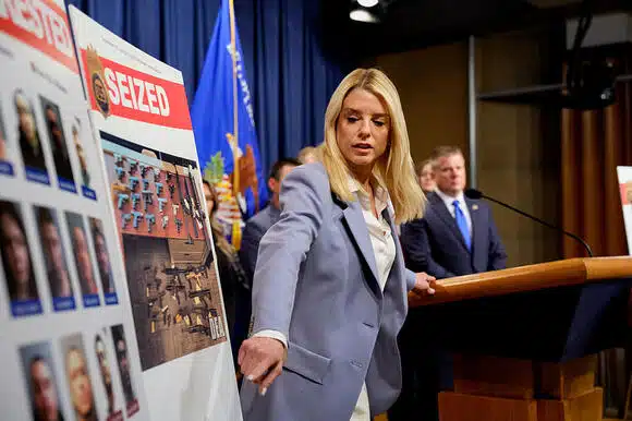 Florida Attorney General Pam Bondi speaks at a press conference announcing the seizure of 11.5 kilograms and 3 million fentanyl pills, the largest in U.S. history, with law enforcement and evidence displayed in the background.