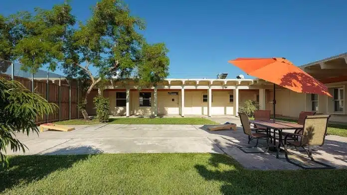 Single-story residential-style rehab facility with palm-tree landscaping at Vista Pines Health, 1300 Hibiscus Drive, Pembroke Pines, FL 33025