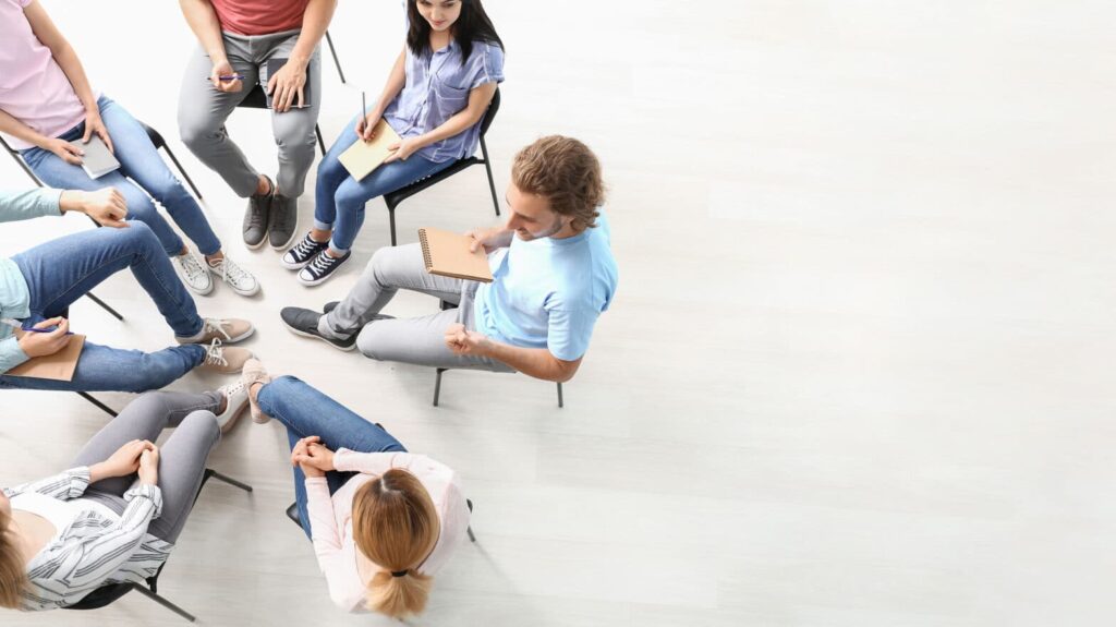 A diverse group of individuals participating in a group therapy session in a comfortable, modern setting - Bedrock Recovery Center A diverse group of individuals participating in a group therapy session in a comfortable, modern setting - Bedrock Recovery Center