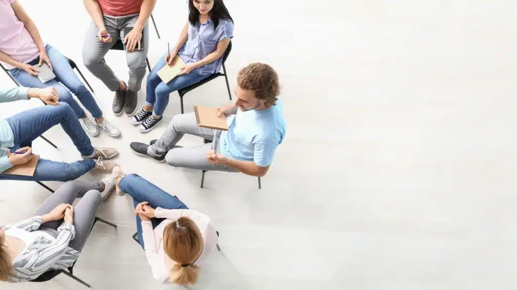 A diverse group of individuals participating in a group therapy session in a comfortable, modern setting - Bedrock Recovery Center A diverse group of individuals participating in a group therapy session in a comfortable, modern setting - Bedrock Recovery Center