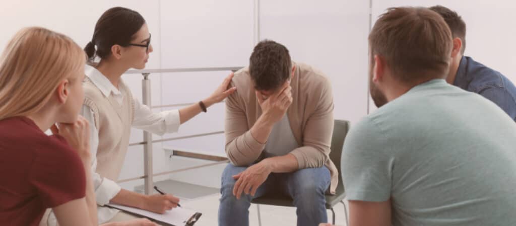 A group of people writing notes together around a table, planning an intervention - how to stage intervention A group of people writing notes together around a table, planning an intervention - how to stage intervention
