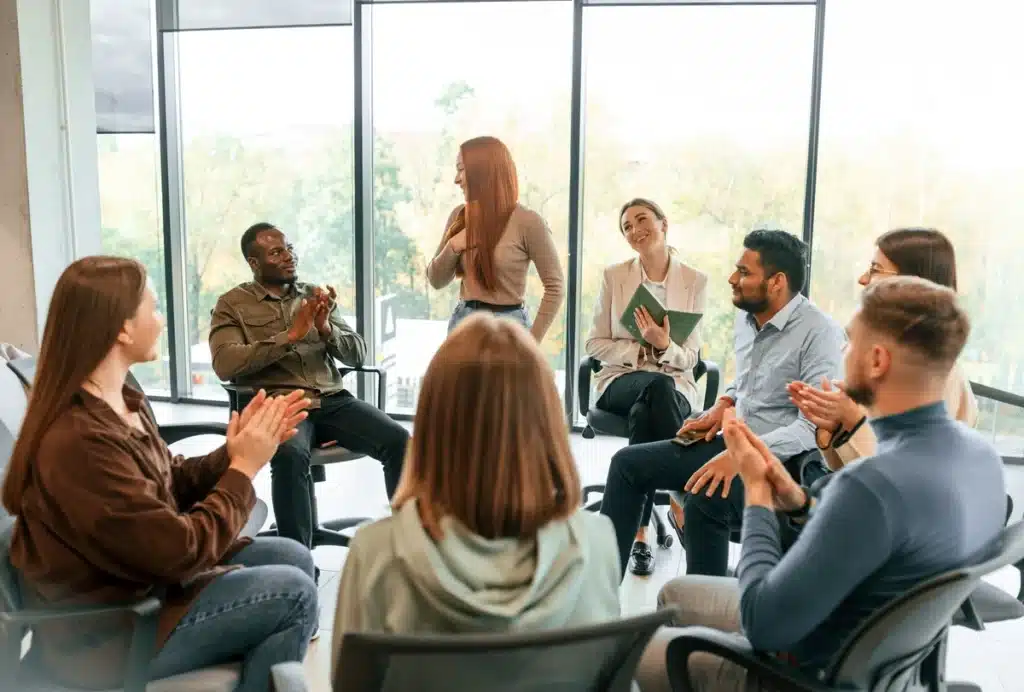 A diverse group of individuals participating in a therapy session, actively listening and engaging in discussion within a comfortable and supportive setting. - drug rehab centers in richmond va